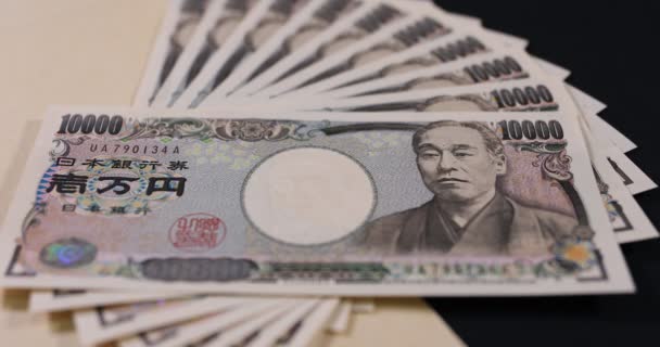 Japonská měna 100,000 jenů s obálkou na černém pozadí náklonu zaostření — Stock video