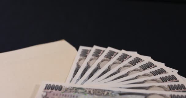 Japanse munt 100.000 yen met enveloppe op de zwarte achtergrond kantelen focussen — Stockvideo