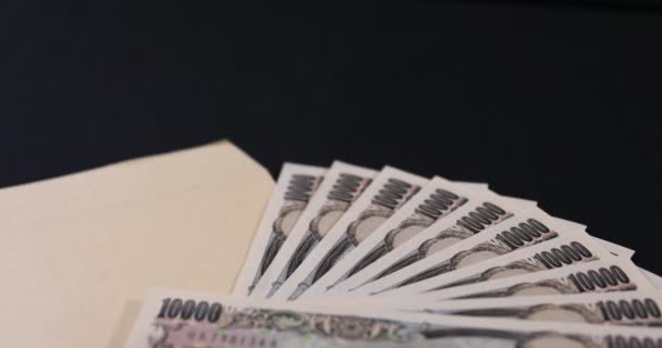 Valuta giapponese 100.000 yen con busta sul fondo nero inclinazione messa a fuoco — Video Stock