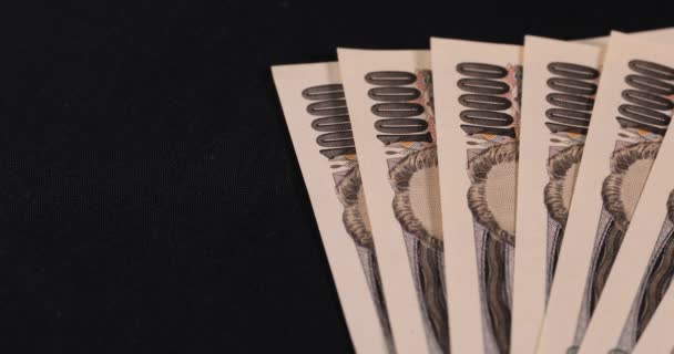 Moneda japonesa 100.000 yenes en el fondo negro panorámica — Vídeo de stock