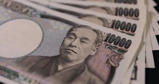Японская валюта 100 000 иен на черном фоне — стоковое видео