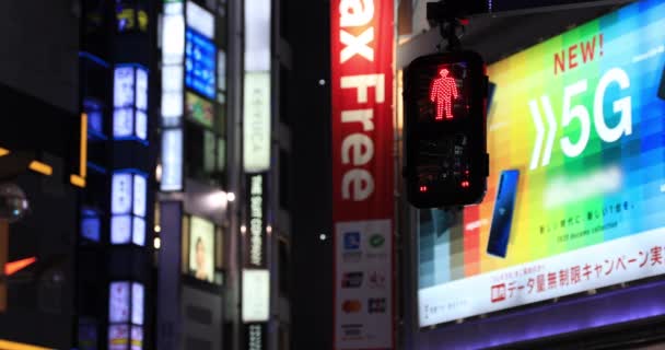 Een verkeerslicht veranderend rood in blauw bij de neon stad in Shinjuku 's nachts — Stockvideo