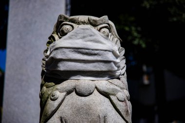 Tokyo 'daki Meguro Fudo Tapınağı' nda maskeli bir koruyucu köpek heykeli.