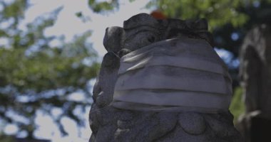 Tokyo 'daki Meguro Fudo Tapınağı' nda maske takan koruyucu köpek heykeli.
