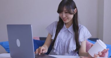 Oturma odasında dizüstü bilgisayarla çalışan bir Japon kadın. Yüksek kalite 4K görüntü. Tokyo Japonya 06.12.2025