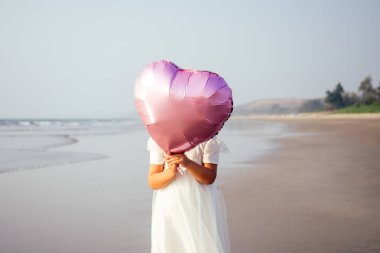 Gün batımında sahilde pembe balonları ile küçük kıvırcık kız