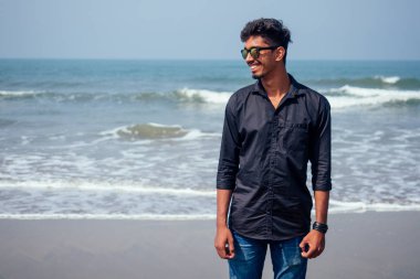 semmertime mutlu Goa Hindistan plajda güneş gözlüğü aktif plaj tatil ile poz genç hindu şık adam. güneş kremi spf koruma konsepti.