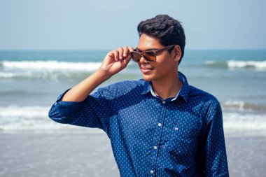semmertime mutlu Goa Hindistan plajda güneş gözlüğü aktif plaj tatil ile poz genç hindu şık adam. güneş kremi spf koruma konsepti.