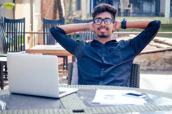 Schöner und erfolgreicher indischer Mann in einem stilvollen gut gekleideten Freiberufler, der mit einem Laptop am Strand arbeitet.Freiberufler und Fernarbeit.Geschäftsmann Student in einem Sommercafé am Ufer des indischen Ozeans — Stockfoto