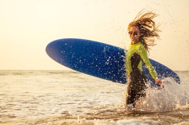 sörf tahtası ile aktif kadınlar tatil tatillerinde su sporu keyfini.rüzgar sörfü sörf okul eğitmeni spor kız. Hint Okyanusu'nda plajda bir dalış kıyafeti dalış kıyafeti turist kadın modeli