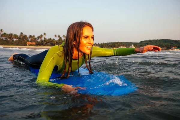 Sport bella donna in tuta subacquea sdraiata su una tavola da surf in attesa di una grande onda .surf ragazza in muta surf in mare al tramonto. capelli bagnati, felicità e libertà vacanza al mare — Foto Stock