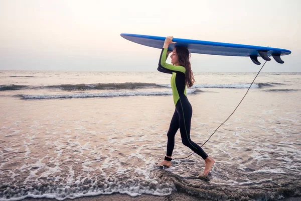 Aktive Frauen mit Surfbrett genießen Wassersport in den Ferien. Sportmädchen in der Surfschule Ausbilder für Windsurfen. Touristenmodel im Taucheranzug am Strand im Indischen Ozean — Stockfoto