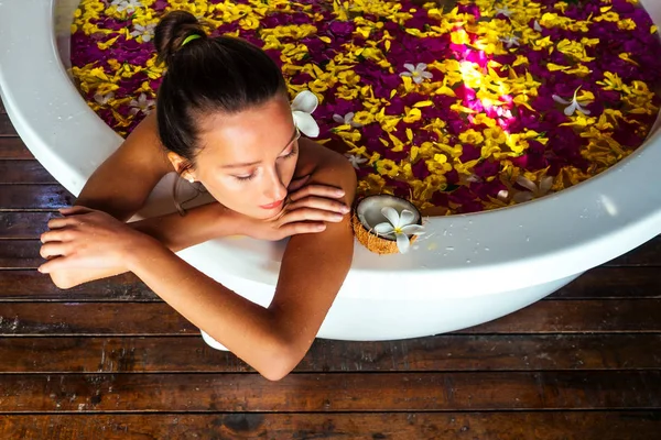 Mujer sexy morena relajante en baño con flores tropicales al aire libre en el complejo hotelero de lujo. Cuidado de la piel orgánica. Hermosa chica descansando en el spa del hotel de masajes y meditation.womens Día 8 de marzo — Foto de Stock