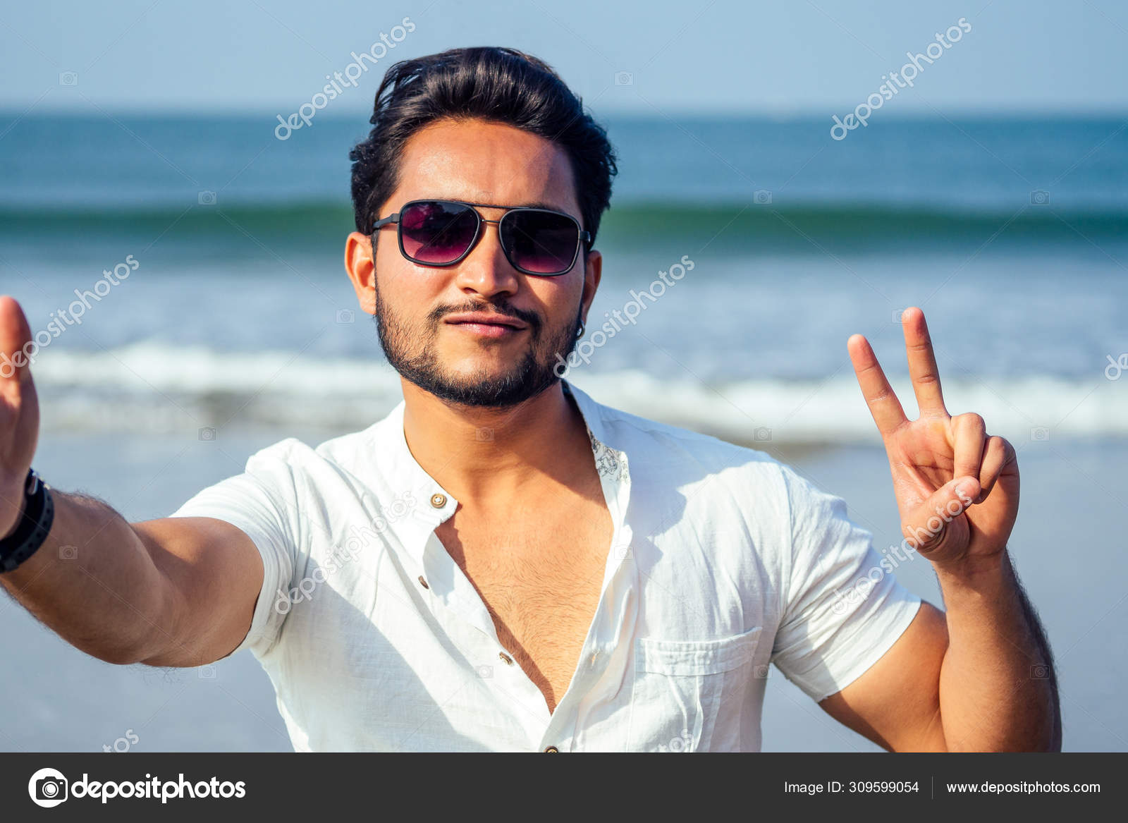 Handsome and young indian male model beard and black hair haircut,fashion  earring and glasses on a background of tropical  portrait man  businessman student relaxing on the beach sea Stock Photo by ©