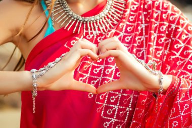Kırmızı saree elleriyle güzel hintli kadın sahilde kalp sembolü. Sevgililer Günü sevgi ve inanç