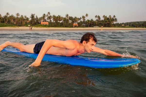 Knappe jonge man genieten van een surf in water. mannelijke surfer in de Oceaan op Surfboard surfen op het strand, freelancer freelance mannen drijven op surfplank in India Goa Ocean. vrijheid en adrenaline concept — Stockfoto