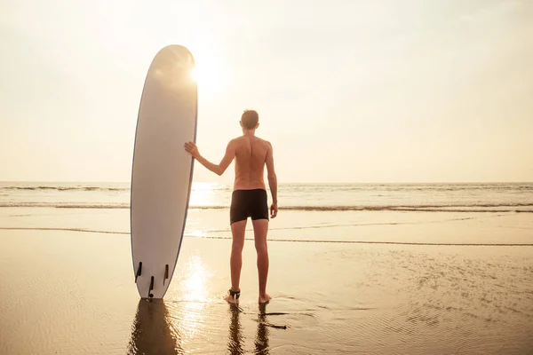 Surfer man staat met surfplank op het strand zomer zonsondergang zee. romantische freelancer mannelijke tropische paradijs rust en vakantie aan de Oceaan bij zonsondergang romantiek — Stockfoto