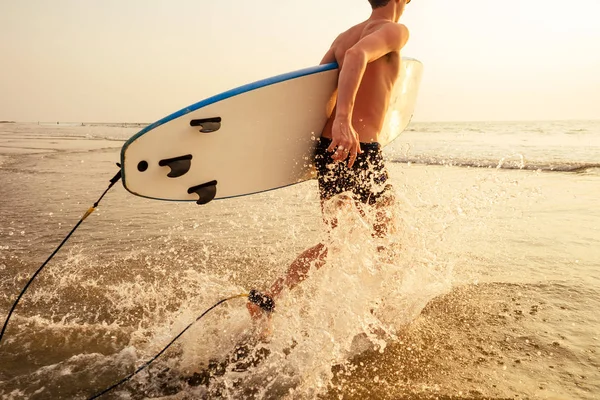 サーファーの男は、ビーチ夏の夕日の海にサーフボードで立っています.ロマンチックなフリーランサー男性熱帯パラダイスの休息と日没ロマンスで海の休日 — ストック写真