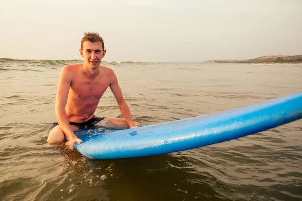 handsome young man enjoying a surf in water.male surfer in the ocean on surf board surfing at beach, freelancer freelance men drifting on surfboard in India Goa ocean.freedom and adrenaline concept