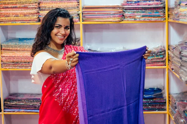 Business lady in rosso tradizionale sari e gioielli negozio di abbigliamento proprietario cashmere yak lana scialli. Venditore femminile in vendita goa india arambol shop.designer sarta sarta ragazza che sceglie tessuto — Foto Stock