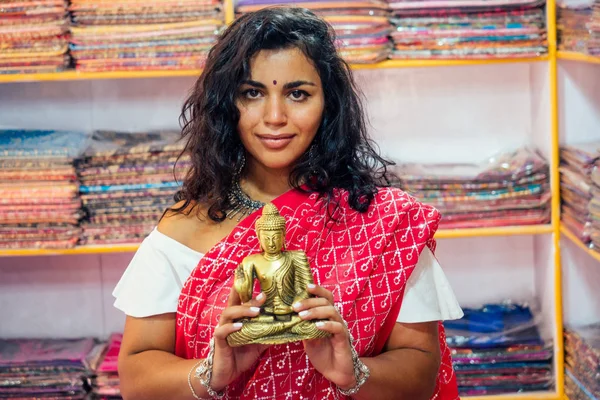Commercio signora indiano venditore tradizione rosso sari souvenir negozio buddha shiva figurina yoga meditation.girl in India nella religione store.beautiful donna con bijouterie gioielli orecchini Delhi Bazaar — Foto Stock