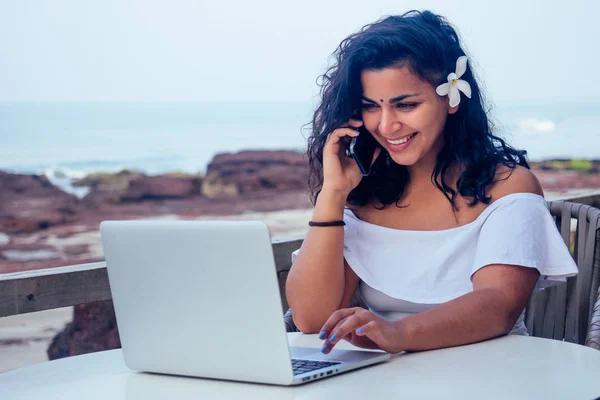 Индийская красивая деловая женщина работает на современном ноутбуке в кафе-ресторане на берегу рая океана.Веб-дизайнер девушка фрилансер в Индии в море .remote работы, концепт-копирайтер — стоковое фото