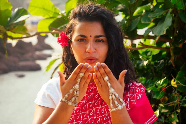 Letní dovolená Valentines den v Indii dívka poslala vzdušný polibek a tvar srdce.krásná žena na sobě indické tradiční oblečení červená svatba saree sari v tropických stromech ráj ostrov moře oceán pláž — Stock fotografie