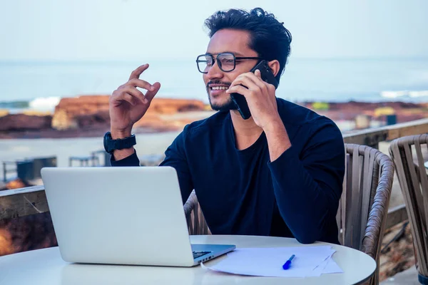 Mann telefoniert Indien Sommerurlaub. Stilvolle junge indische männliche Freiberufler arbeiten mit Laptop freiberuflich Surfen online.businessat Remote-Arbeit am Strand.dream job.online Kauf Verkauf — Stockfoto