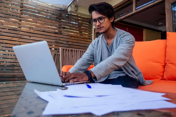 Handsome and young successful indian man freelancing surfing remote work with a laptop on the beach by the ocean.india businessman freelance programming online copywriter paradise landscape dream job — Stock Photo, Image