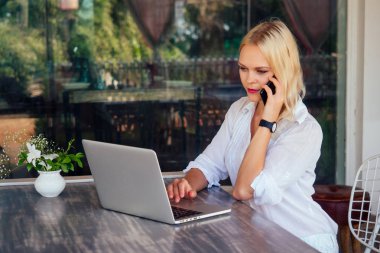 başarılı genç kadın öğle yemeği molası sırasında telefonda sohbet. Bir yaz açık hava kafede telefonda konuşurken bir iş kadını samimi görüntü