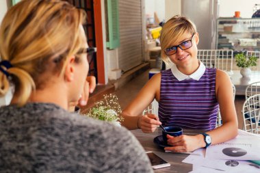 erkek meslektaşının önünde dizüstü bilgisayar ile masada oturan gülümseyen kadın ofis çalışanı.