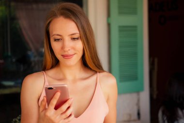 model kadın uzun saçlı telefon tutar ve elinde erkek arkadaşları ile metin yazarak konuşuyor . parkta arkadaşlarıyla sohbet aşık kız, konsept yüz id