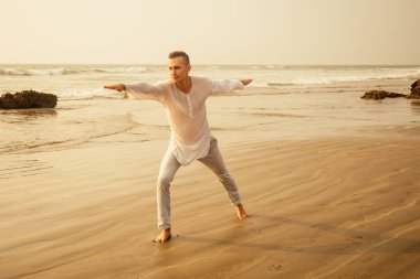 beyaz gömlek ve pantolon adam hareket yoga savaşçı sabah güneş ışığına karşı siluet.işadamı dengesi karşı sahilde poz