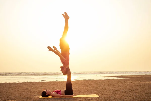 Два человека практикуют йогу в свете заката на пляже Гоа Индиа. женский и мужской акро-йог тантра тантра летающая копия — стоковое фото