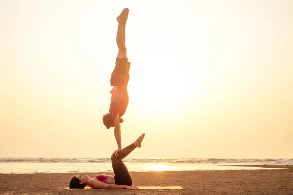 고아 인도 해변에서 일몰 빛에 요가를 연습 하는 두 사람. 암컷과 남성 아크로 요기 탄트라 비행 copyspce — 스톡 사진