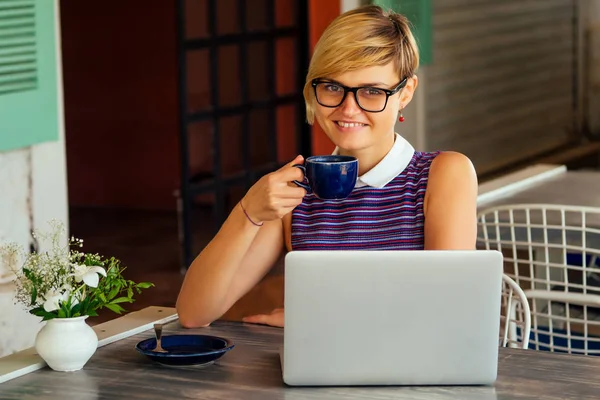 Web Designer remote working concept.Successful stylish female tourist working at modern laptop computer sitting at a table in coffee shop cafe restaurant on sea shore.freelance freelancing remote work