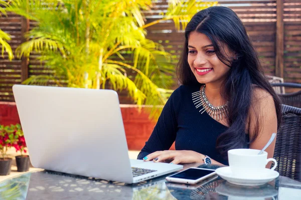 Идея кофе-брейка. Молодая индийская предпринимательница пользуется планшетным компьютером в летнем кафе в саду — стоковое фото
