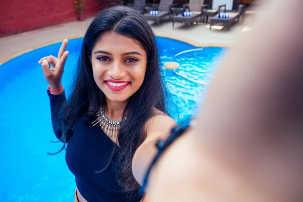 Красивая индийская женщина зубастая белая улыбка селфи портрет на смартфоне камеры летнее кафе у бассейна Гоа — стоковое фото