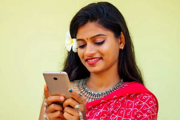 Feliz india dama de negocios sonrisa de dientes blancos en ropa tradicional india sari vestido de novia rojo sosteniendo un gadget en la mano utilizando la aplicación de teléfono en las rocas tropicales isla vacaciones india Bay.girl cara id —  Fotos de Stock