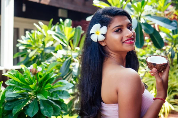 Mulher indiana aplicando óleo de coco morena escura cabelo longo em uma mão no parque de verão verde natureza tropical — Fotografia de Stock