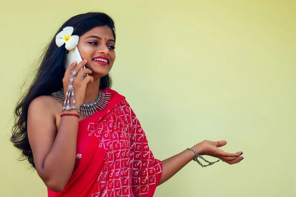 Gelukkig India Business Lady wit toothy glimlach in traditionele Indiase Sari kleding rode trouwjurk met een gadget in de hand met behulp van de telefoon-app in Tropic Island Rocks vakantie Indian Bay. meisje praten — Stockfoto