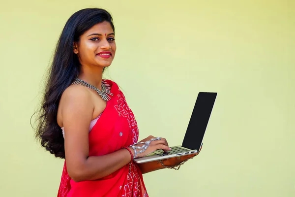 Trabajo de sueño concepto de trabajo remoto. mujer de negocios india en sari rojo con estilo, peinado rizado, sonrisa blanca dentada y flor en el pelo que trabaja con un ordenador portátil mientras está sentado en un café de verano por el mar —  Fotos de Stock