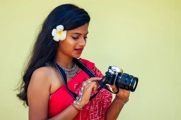 Mujer fotógrafa de la India fotografiando con cámara digital en la playa.hermosa mujer india en sari rojo tradicional en el paraíso tropical mar tomando fotos de la sesión de fotos del paisaje —  Fotos de Stock