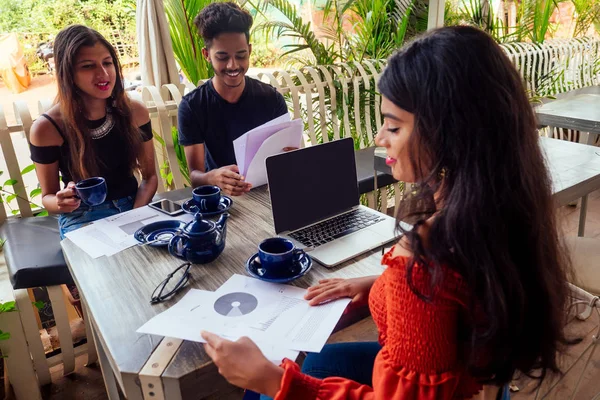 Multicultural group of people discussing by laptop in summer cafe surfing online freelancer freelance