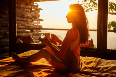 Beautiful woman with cup of coffee tea enjoying the view from the balcony on tea plantation jungle at India Kerala Goa wildernest nature spa resort