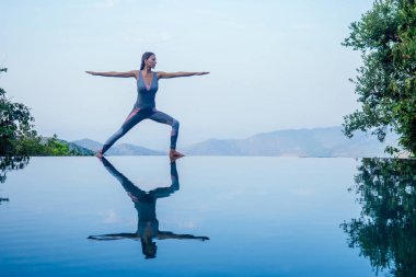 Güzel kadın uygulama yoga hindistan goa vahşi doğa tesisi güzel doğa manzarası önünde sabah dağ zirvesinin üzerindeki sonsuzluk havuzunda poz .dağlarda romantizm gün doğumu