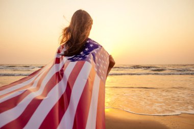yaz romantik gün batımında ulusal Amerikan bayrağı kapak okyanus plaj tatil seyahat tutan arka genç esmer kadın kişi görünümü . Amerika bağımsızlık günü kavramı