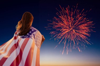 4 Temmuz'da Amerikan bayrağını tutan genç mutlu vatansever kız selamına bakıyor.