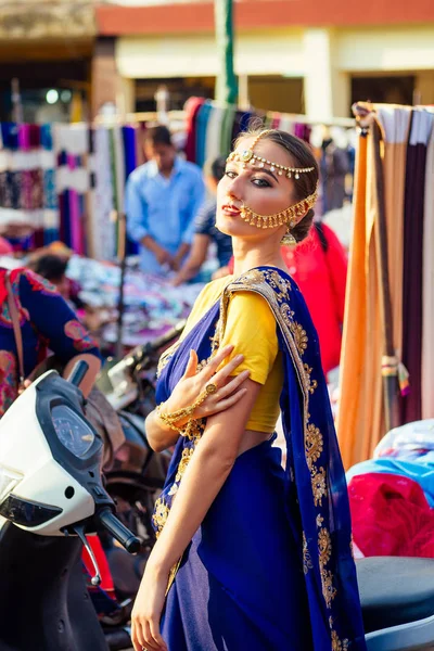 India hermosa mujer caucásica tradicional modelo dress.hindu azul con conjunto de joyas de oro kundan bindi y piercing anillo de la nariz debajo de la sesión de fotos de moda en la calle entre las motocicletas y el mercado de Mapusa —  Fotos de Stock