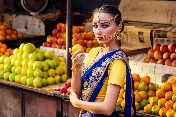 Indiai kaukázusi nő a hagyományos ruhában. hindu modell Golden Kundan ékszerek set Bindi fülbevaló és az orr gyűrű piercing Nath kiválasztása gyümölcsök vásárló egy szupermarket gyümölcs üzlet. egzotikus eladás Kerala Goa — Stock Fotó